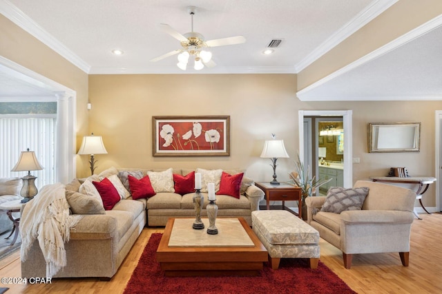 living room with ornate columns, ceiling fan, crown molding, and light wood-type flooring