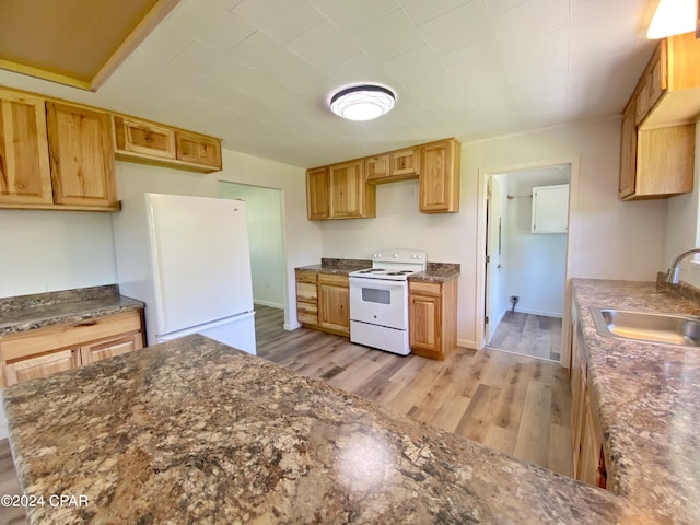 kitchen featuring dark stone countertops, light hardwood / wood-style floors, white appliances, and sink