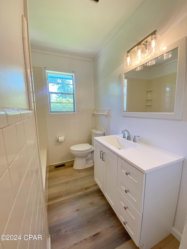 bathroom with wood-type flooring, tile walls, ornamental molding, oversized vanity, and toilet