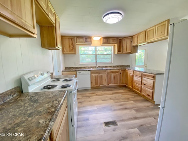 kitchen with dark stone counters, white appliances, sink, and light wood-type flooring