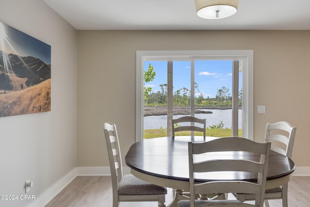 dining space with a water view, plenty of natural light, and light hardwood / wood-style flooring