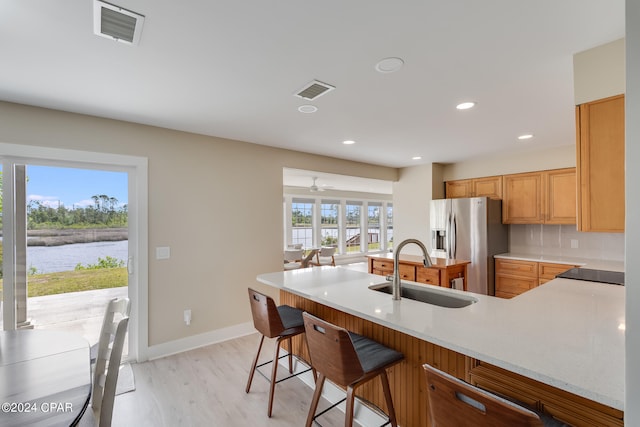 kitchen featuring light wood-type flooring, sink, ceiling fan, stainless steel fridge with ice dispenser, and tasteful backsplash