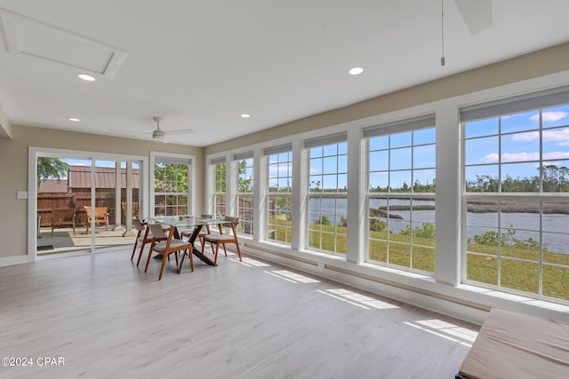 unfurnished sunroom with a water view, ceiling fan, and a wealth of natural light