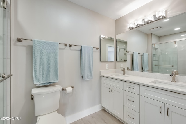 bathroom featuring vanity, toilet, hardwood / wood-style flooring, and a shower with shower door