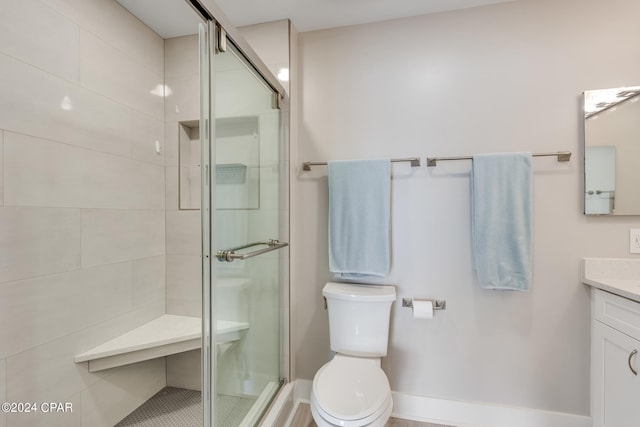 bathroom featuring vanity, toilet, and a shower with door