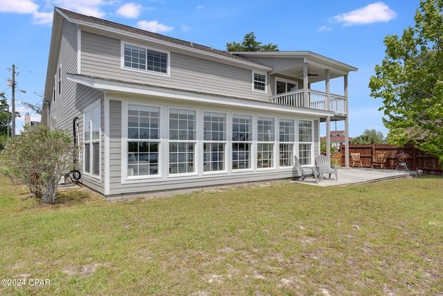 back of house with a balcony, a patio area, and a yard