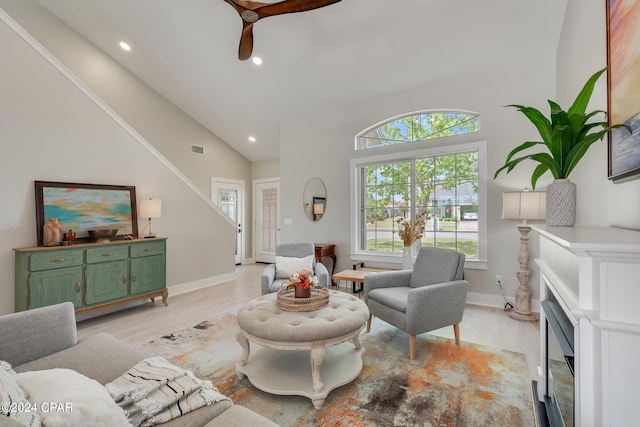 living room with a healthy amount of sunlight, ceiling fan, high vaulted ceiling, and light hardwood / wood-style floors