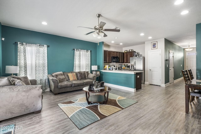 living room with light hardwood / wood-style floors and ceiling fan