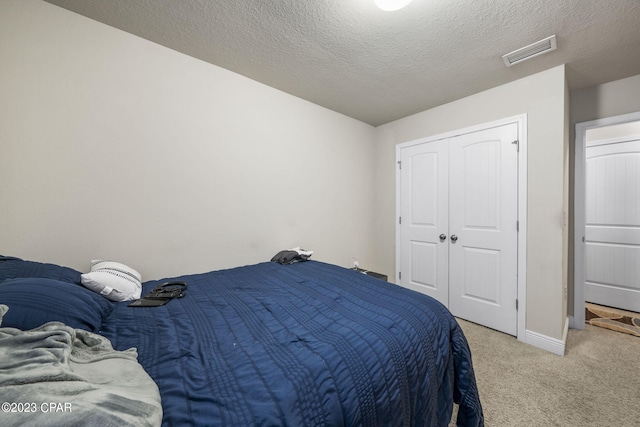 bedroom with light carpet, a closet, and a textured ceiling