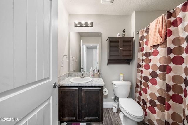 bathroom featuring wood-type flooring, toilet, a textured ceiling, and large vanity