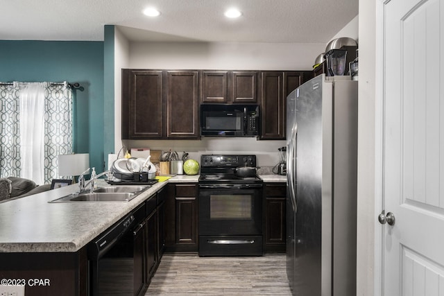 kitchen featuring light wood-type flooring, black appliances, sink, dark brown cabinetry, and a textured ceiling