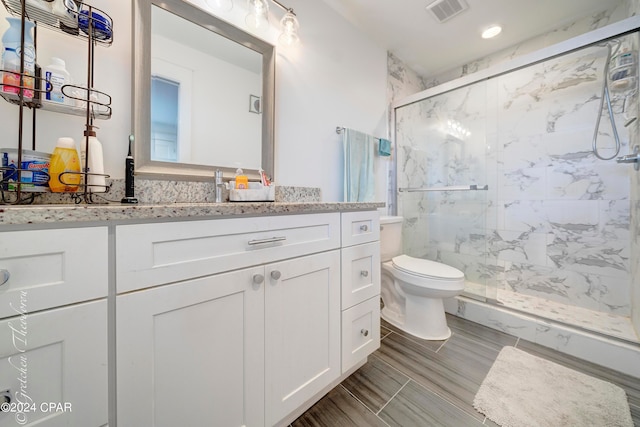 bathroom featuring a shower with door, toilet, tile floors, and vanity