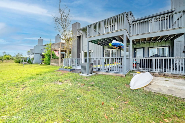 rear view of house featuring a balcony, central air condition unit, and a lawn