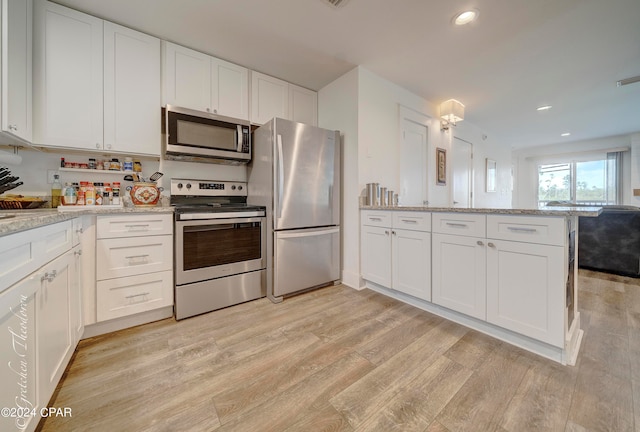 kitchen with white cabinets, light hardwood / wood-style flooring, and stainless steel appliances