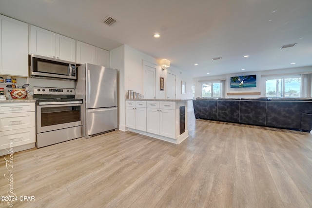 kitchen featuring white cabinets, stainless steel appliances, light hardwood / wood-style floors, and light stone counters