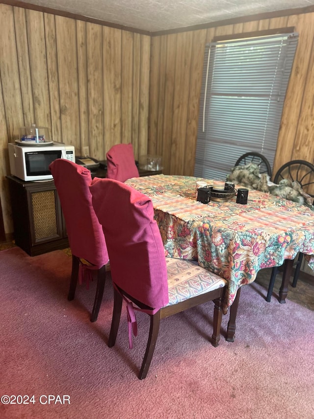 dining area featuring dark colored carpet, wood walls, and a textured ceiling