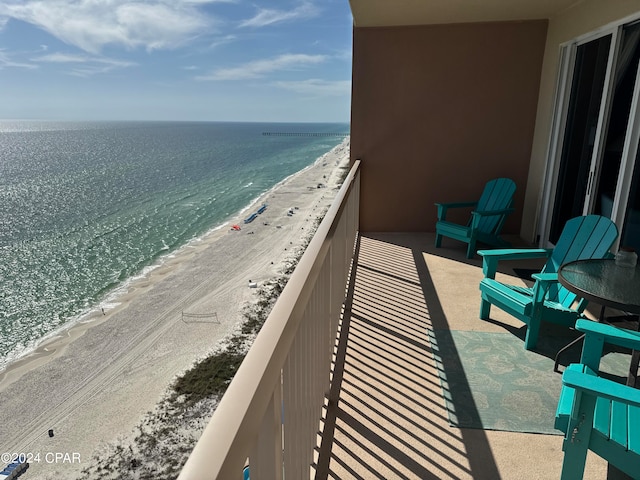 balcony with a water view and a view of the beach