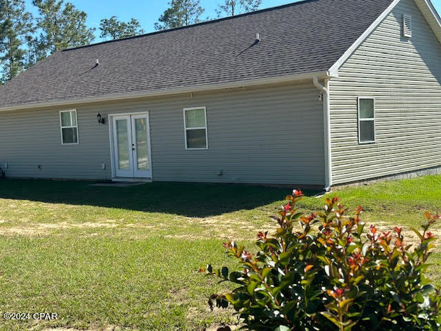 rear view of property featuring french doors and a lawn