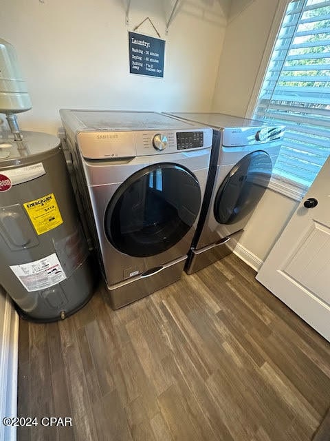 clothes washing area featuring dark hardwood / wood-style floors, electric water heater, and washer and clothes dryer