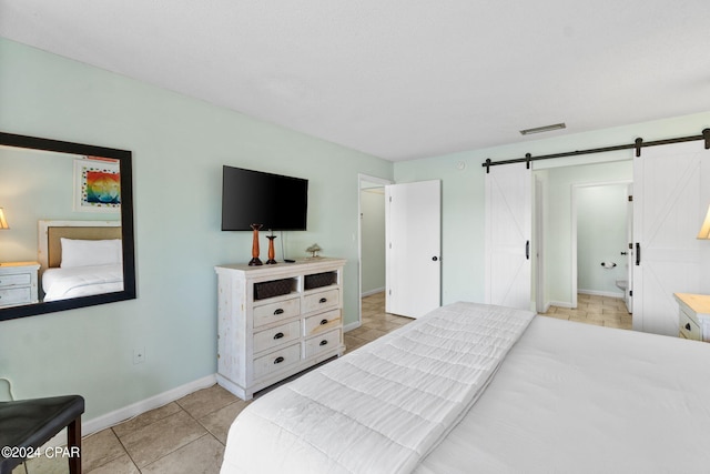 tiled bedroom featuring a barn door