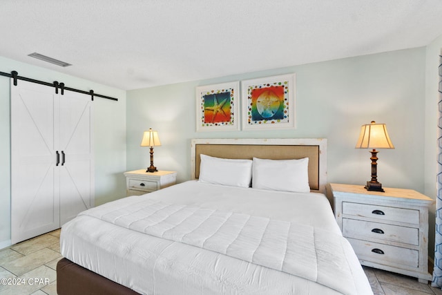 tiled bedroom featuring a barn door and a textured ceiling