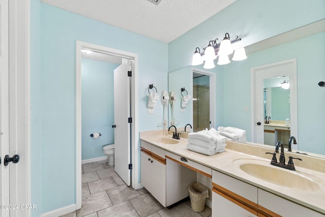 bathroom featuring toilet, tile flooring, double vanity, and a textured ceiling