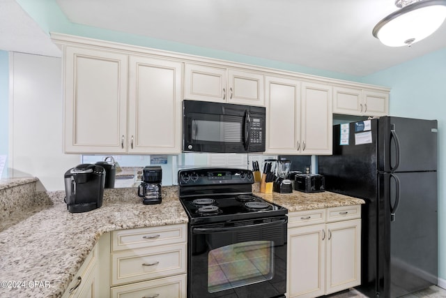 kitchen with cream cabinetry, black appliances, and light stone countertops