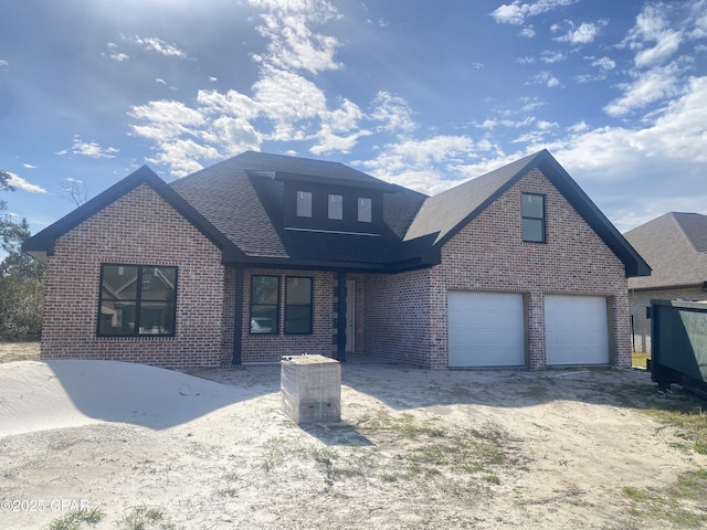 traditional-style home featuring dirt driveway, brick siding, and roof with shingles