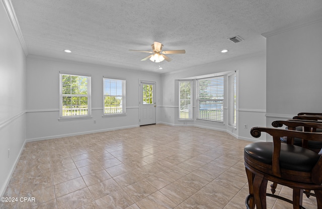 interior space featuring a textured ceiling, ceiling fan, light tile patterned floors, and crown molding