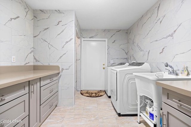 laundry room with tile walls, light tile patterned floors, and washing machine and clothes dryer