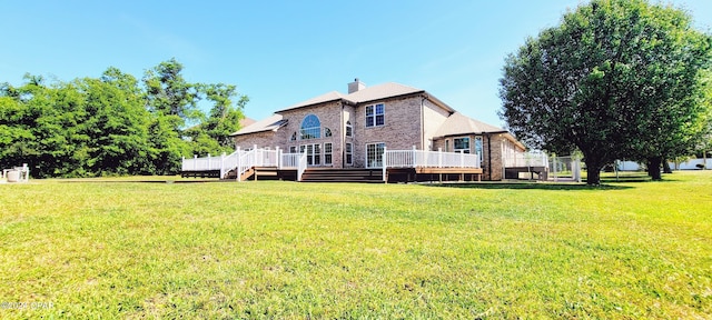 rear view of house featuring a wooden deck and a yard