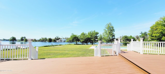 wooden deck featuring a swimming pool, a lawn, and a water view