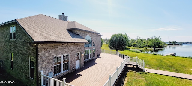 back of house featuring a deck with water view and a lawn