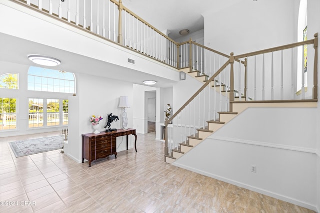 stairs featuring a towering ceiling and light tile patterned floors