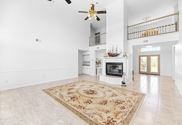 tiled living room featuring ceiling fan, french doors, and a towering ceiling