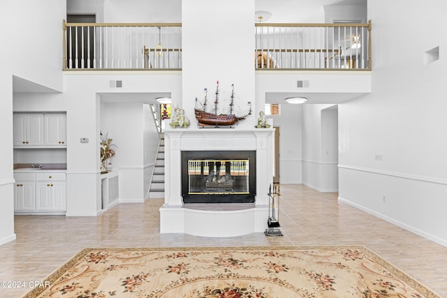 living room with a multi sided fireplace, a high ceiling, and light hardwood / wood-style flooring