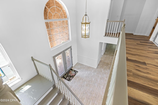 entrance foyer with a towering ceiling, a chandelier, and wood-type flooring