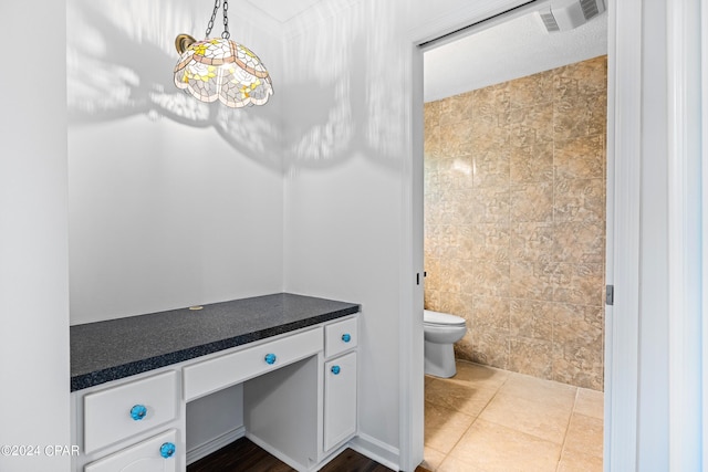 bathroom with toilet, tile patterned flooring, vanity, and tile walls