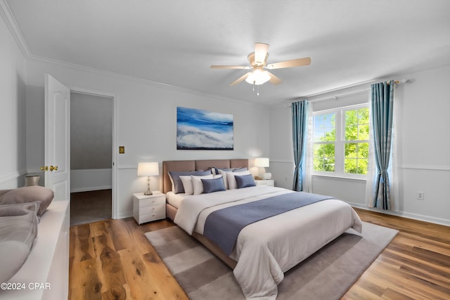 bedroom with light hardwood / wood-style floors, ornamental molding, and ceiling fan