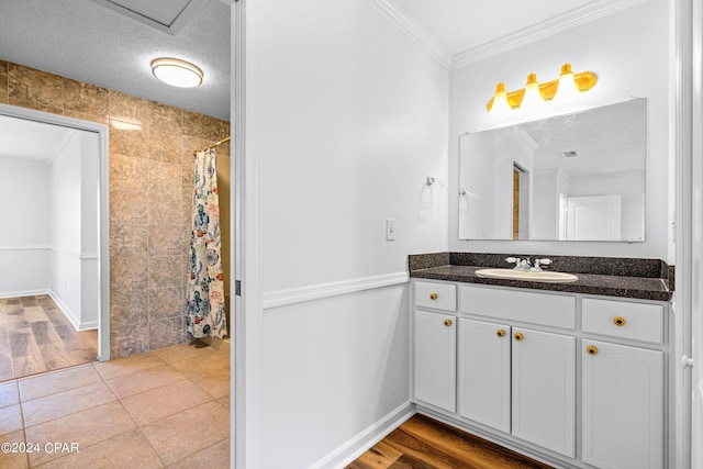 bathroom with tile patterned floors, a textured ceiling, crown molding, and vanity