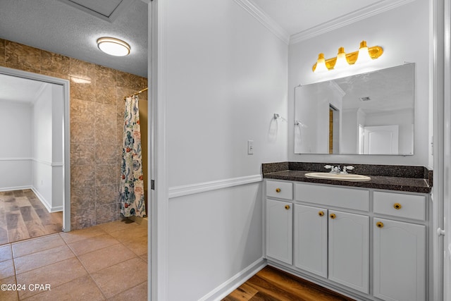 bathroom featuring tile patterned floors, a textured ceiling, vanity, tile walls, and crown molding