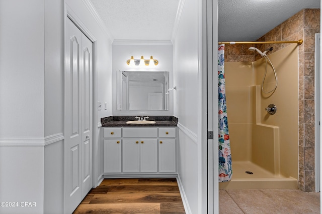 bathroom with a shower with shower curtain, vanity, crown molding, a textured ceiling, and wood-type flooring