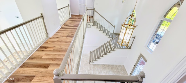 staircase with light hardwood / wood-style floors and a towering ceiling