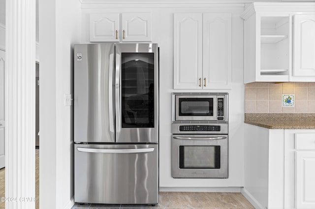 kitchen with dark stone counters, stainless steel appliances, white cabinetry, and tasteful backsplash