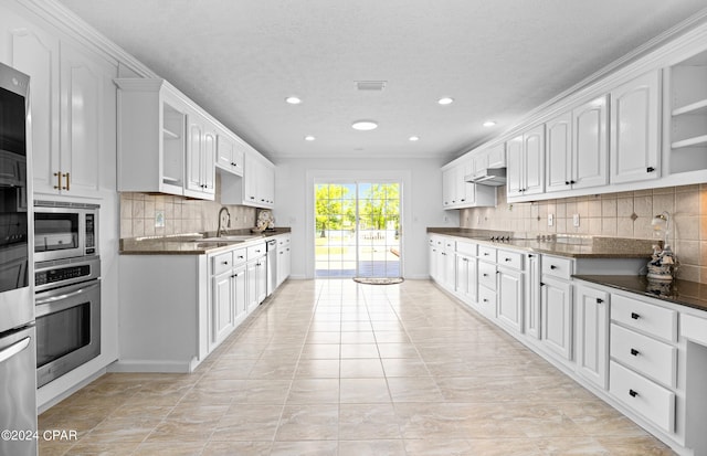 kitchen with appliances with stainless steel finishes, white cabinetry, dark stone countertops, and tasteful backsplash