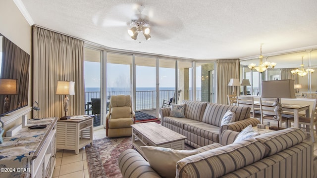 living room with ceiling fan with notable chandelier, a textured ceiling, a water view, and ornamental molding