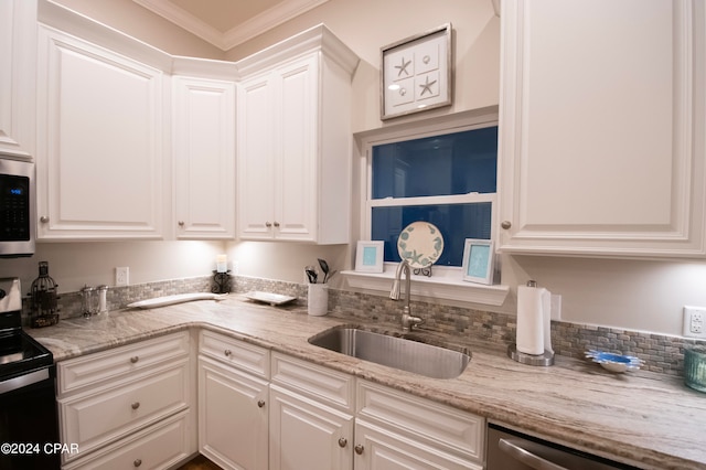 kitchen with light stone counters, appliances with stainless steel finishes, sink, white cabinetry, and ornamental molding