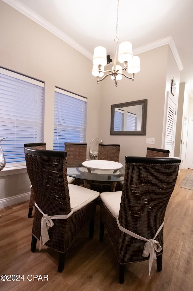 dining area featuring wood-type flooring, crown molding, and an inviting chandelier