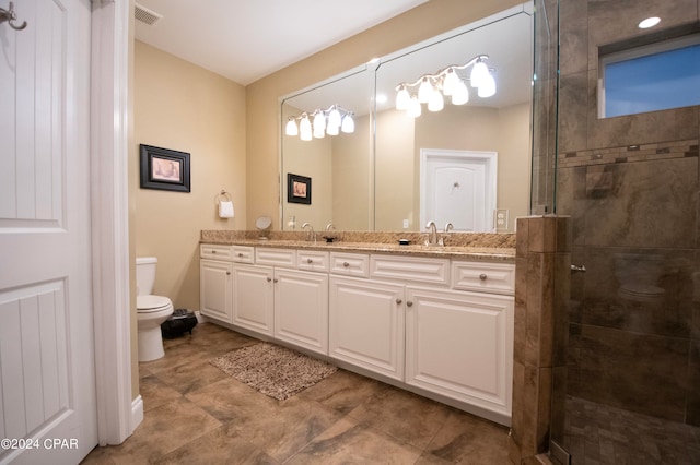 bathroom featuring tile flooring, a shower with door, toilet, and dual bowl vanity