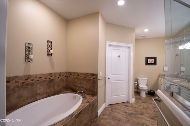 bathroom featuring tile flooring, vanity, toilet, and tiled bath